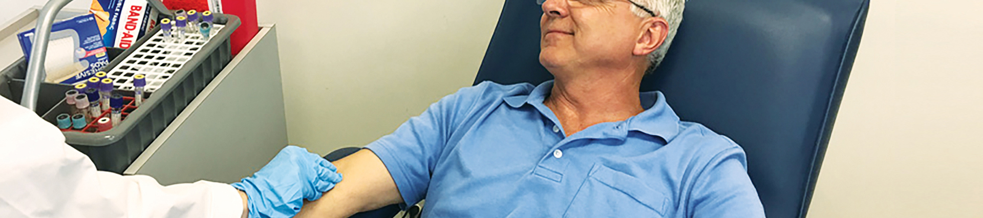 Man sitting in a blood draw chair having his blood drawn